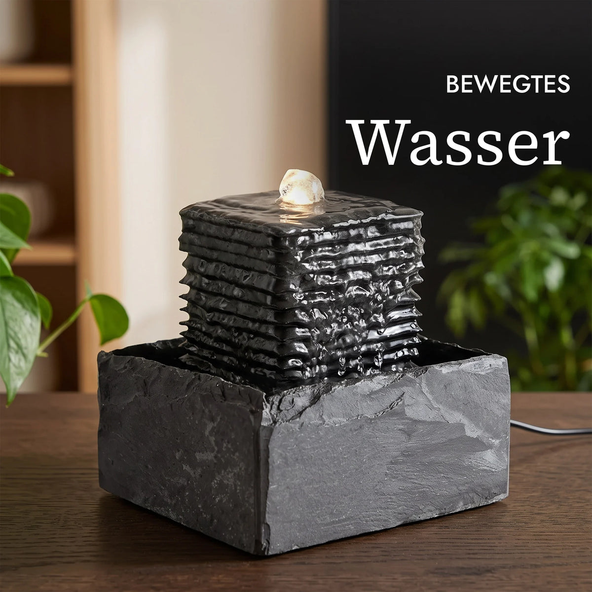 Bewegtes Wasser läuft über den gerippten Schiefer des Zimmerbrunnens SHANTI (KI-Inhalte)