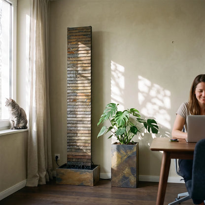 CLIMAQUA AVA XL Wasserwand aus Schiefer im Arbeitszimmer am Fenster, daneben ein PYLO 60 Pflanzgefäss mit Monstera - CLIMAQUA (KI-Inhalte)