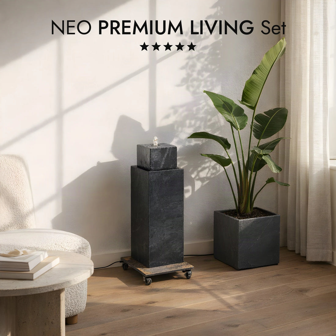Brunnensäule NEO ANTHRAZIT PREMIUM LIVING Set auf dem Rolluntersetzer ROLO im hellen Wohnzimmer, daneben CUBI 31 mit Strelitzie (KI-Inhalte)
