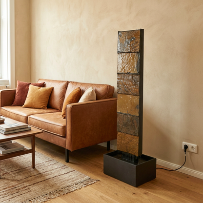 VIO L Rusty Wasserwand aus Schiefer neben einem Ledersofa im Wohnzimmer - CLIMAQUA (KI-Inhalte)